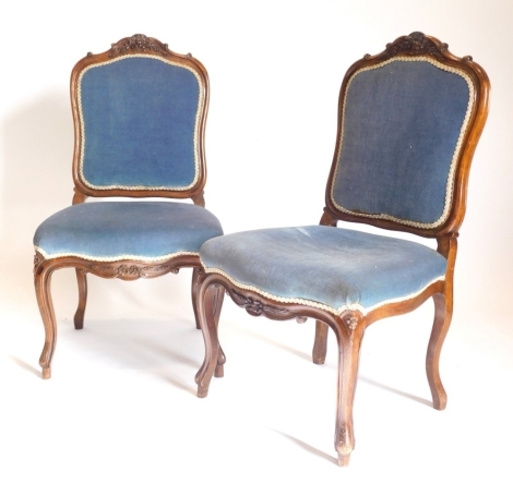 A pair of continental walnut dining chairs, each with a cartouche shaped carved padded back, a padded seat, on cabriole legs.