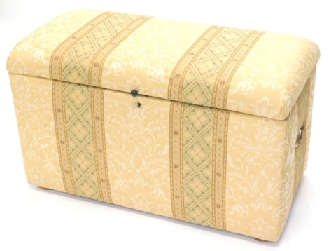 A padded and upholstered Ottoman, the hinged lid enclosing a lined interior, the base with two brass drop handles, 92cm wide.