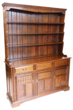 An oak dresser, the raised back with three plate or Delft shelves the base with three frieze drawers above three panelled doors on bracket feet, 153cm wide.