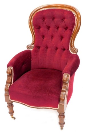 A Victorian mahogany spoon back open armchair, with button back arms and over stuffed serpentine seat in crimson material on turned front legs, 108cm high.