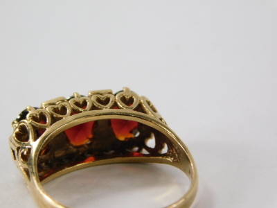 A ladies 9ct gold garnet dress ring, with three claw set faceted cut stones on a pierced shank decorated with hearts, size N-O, 3.3g all in. - 6