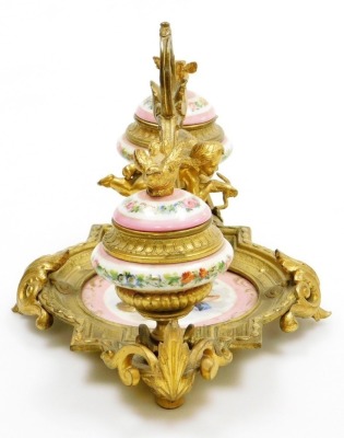 A 19thC French porcelain and ormolu mounted desk stand, possibly Sevres, the central dish painted with a cherub against a pink ground, flanked by two ink pots each cast with bird finials holding a letter in each beak, the porcelain ink pots decorated with - 11