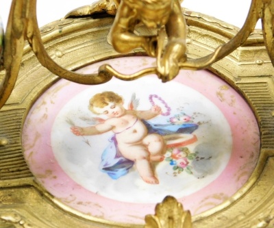 A 19thC French porcelain and ormolu mounted desk stand, possibly Sevres, the central dish painted with a cherub against a pink ground, flanked by two ink pots each cast with bird finials holding a letter in each beak, the porcelain ink pots decorated with - 12