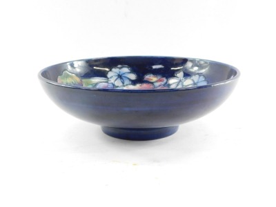 A Moorcroft pottery bowl decorated in the Frilled and Slipper Orchid pattern, against blue ground, painted and impressed marks, 26cm diameter. (AF) - 5