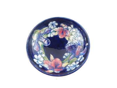 A Moorcroft pottery bowl decorated in the Frilled and Slipper Orchid pattern, against blue ground, painted and impressed marks, 26cm diameter. (AF) - 6