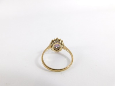 An amethyst and CZ dress ring, with central oval cut amethyst in claw setting, surrounded by halo of tiny CZ stones, in a raised basket setting, yellow metal, unmarked, ring size P, 2.4g all in. - 4