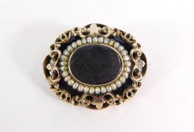 A Victorian mourning brooch, the oval brooch with black enamel outer border and central locket panel surrounded by seed pearls, with applied gold raised relief and a floral inscribed back, on single pin back with pendant loop, 22.7g all in, 4.5cm wide. (A - 3