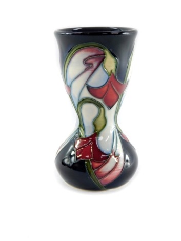 A Moorcroft pottery vase, of waisted form, decorated with delicate red and white flowers against blue ground, second, c2006/08, monogrammed, impressed and painted marks, 11cm high.