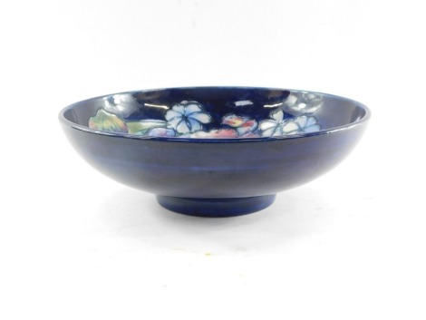 A Moorcroft pottery bowl decorated in the Frilled and Slipper Orchid pattern, against blue ground, painted and impressed marks, 26cm diameter. (AF)