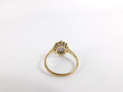 An amethyst and CZ dress ring, with central oval cut amethyst in claw setting, surrounded by halo of tiny CZ stones, in a raised basket setting, yellow metal, unmarked, ring size P, 2.4g all in. - 2