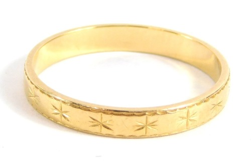 A wedding band, with star hatched design, yellow metal, unmarked, ring size N½, 2g.
