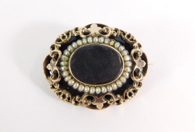 A Victorian mourning brooch, the oval brooch with black enamel outer border and central locket panel surrounded by seed pearls, with applied gold raised relief and a floral inscribed back, on single pin back with pendant loop, 22.7g all in, 4.5cm wide. (A