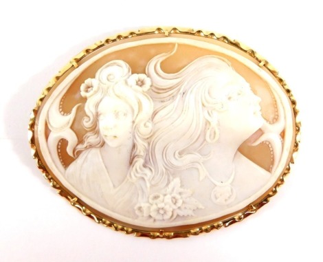 An Italian 19thC shell cameo brooch, with oval shaped cameo, in a raised relief of two maidens, with a yellow metal outer frame and single pin back, stamped 585, 7.5cm x 6cm, 24.8g all in.