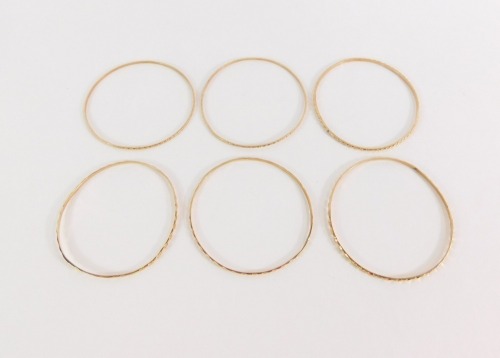 Four Parisian bangles, each of hammered design, yellow metal, unmarked, 28.4g all in, 5cm diameter.