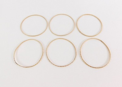 Four Parisian bangles, each of hammered design, yellow metal, unmarked, 28.4g all in, 5cm diameter.
