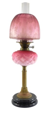 A duplex late 19thC Burmese glass and brass oil lamp, with a fluted column and moulded glass reservoir, clear glass chimney and etched cranberry glass shade, 65cm high.