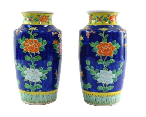 A pair of Japanese mid century porcelain vases, of shouldered ovoid form, decorated with exotic birds, prunus blossom and flowers against a cobalt blue ground, 35cm high.