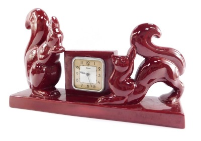 A French mid pottery mantel clock, scout square dial bearing Arabic numerals, clockwork movement, the square clock case flanked by a pair of squirrels, raised on a rectangular base, 38cm wide.