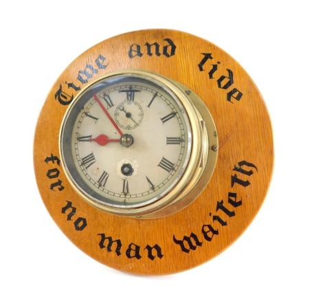 A brass cased early 20thC ship's clock, circular enamel dial, bearing Roman numerals, subsidiary seconds dial, on a oak backing, painted with 'Time and Tide for no man waiteth', with key, 31cm diameter.