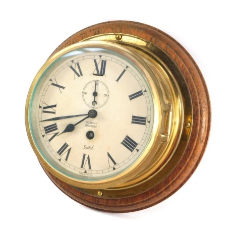 A Sestrel early 20thC brass cased ships porthole clock, for Olsen's of Grimsby, circular dial bearing Roman numerals, subsidiary seconds dial, with key, 23cm diameter.