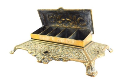 A Victorian brass desk stand, the hinged box top embossed with classical urn, flowers and foliate scrolls, opening to reveal five graduated compartments, the base embossed with scrolls, 22cm wide.