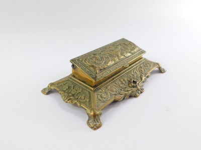 A Victorian brass desk stand, the hinged box top embossed with classical urn, flowers and foliate scrolls, opening to reveal five graduated compartments, the base embossed with scrolls, 22cm wide. - 2