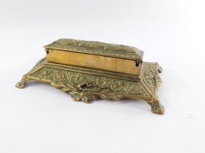 A Victorian brass desk stand, the hinged box top embossed with classical urn, flowers and foliate scrolls, opening to reveal five graduated compartments, the base embossed with scrolls, 22cm wide. - 3