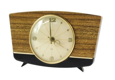 A Smiths 1950's mantel clock, the circular cream dial bearing Arabic numerals at quarters, clockwork movement, the brown bakelite case with faux wood front, 22cm wide.