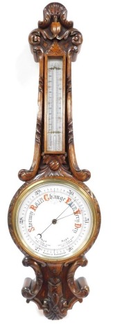 A Victorian oak aneroid wheel barometer, with thermometer, the case carved with leaves and c scrolls, 83cm high.