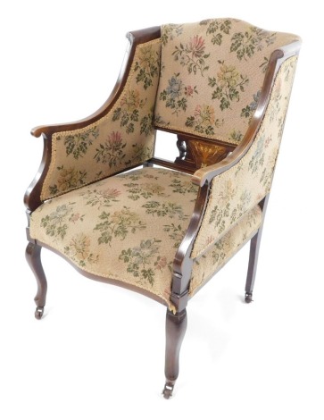 A Victorian mahogany and inlaid armchair, with over stuffed floral upholstery, raised on cabriole legs on castors.