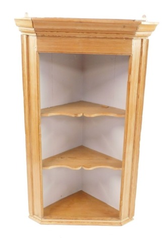 A pine hanging corner cabinet, the moulded cornice above two shelved sections, 126cm high, 70cm wide, 49cm deep. (AF)