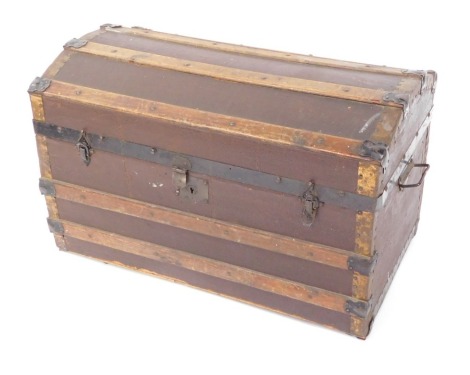 An early 20thC domed top travel trunk, with wooden strap work, and decorative paper lined interior, 49cm high, 77cm wide, 42cm deep.