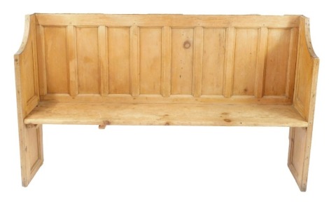 A pine pew, the eight paneled back with carved supports, 103cm high, 174cm wide, 35cm deep.