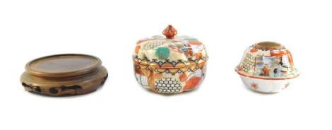 A Japanese kutani box and cover, of lobed form decorated with figural reserves, together with a matching candle holder, and a Chinese wooden stand. (3)