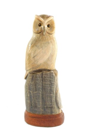 A carved horn figure of an owl on a perch, on wooden base, 26cm high.