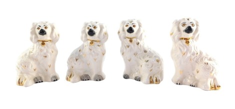 Four Royal Doulton figures of Staffordshire type flatback spaniels, each in white picked out in gilt, 14cm high.