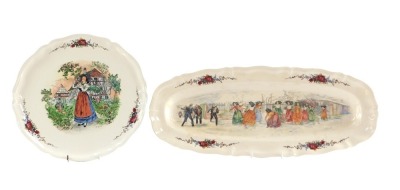 Two Sarreguemines Obernai pottery dishes, one circular depicting a lady near a country cottage, 35cm diameter, and another of figures having a snowball fight in the street, oblong, 60cm x 24cm.