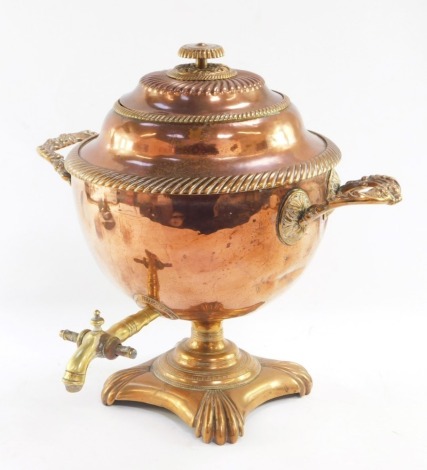 A Regency copper and brass tea urn, the reeded top and borders, on fluted handles, with brass tap, and shell cast feet, 40cm high.