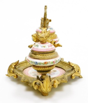 A 19thC French porcelain and ormolu mounted desk stand, possibly Sevres, the central dish painted with a cherub against a pink ground, flanked by two ink pots each cast with bird finials holding a letter in each beak, the porcelain ink pots decorated with - 2