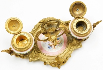 A 19thC French porcelain and ormolu mounted desk stand, possibly Sevres, the central dish painted with a cherub against a pink ground, flanked by two ink pots each cast with bird finials holding a letter in each beak, the porcelain ink pots decorated with - 6