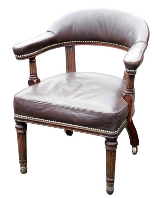 A 19thC mahogany and gilt metal library chair, upholstered in studded brown leather with turned fluted supports and similar tapering legs, with gilt brass mounts and castors.