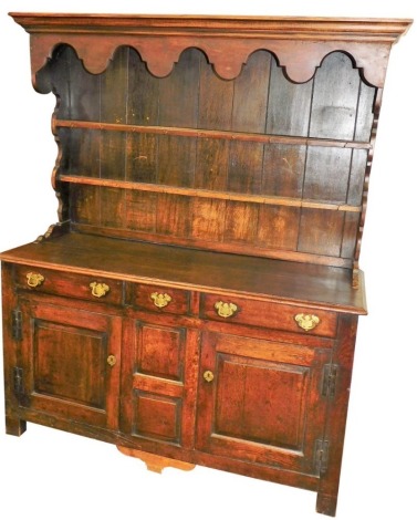 A late 18th/early 19thC oak dresser, the associated raised back with a later cornice above a shaped crest and two shelves, the base with an arrangement of three drawers and two panelled doors, with brass handles and H shaped hinges, on stiles, 184cm high,