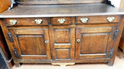 A late 18th/early 19thC oak dresser, the associated raised back with a later cornice above a shaped crest and two shelves, the base with an arrangement of three drawers and two panelled doors, with brass handles and H shaped hinges, on stiles, 184cm high, - 2