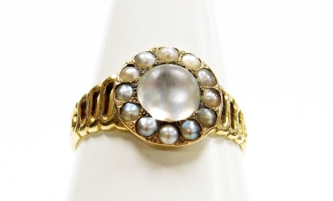 A Victorian moonstone dress ring, the circular central panel set with a large moonstone surrounded by seed pearls, on a four weaved band, yellow metal stamped 20, ring size P½, 2.6g all in.