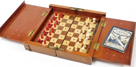 An early 20thC mahogany cased travelling chess set, with white and red stained ivory chess pieces, board 18cm x 18cm.