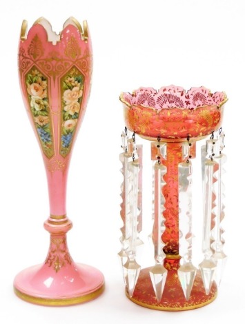 A Victorian cranberry glass lustre, gilt decorated with ferns and scrolling leaves, with prismatic glass drops, 25.5cm high, together with a 19thC Bohemian glass vase, decorated with reserve panels of trailing roses and other flowers, gilt foliate heighte