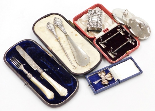 A group of small silver, to include a late Victorian silver match cover, repousse decorated with vacant cartouche, birds, scrolls, etc., Chester 1899, a three leaf clover brooch, 5cm high, boxed, a pair of knife rests, condiment lids, button hook, etc., w