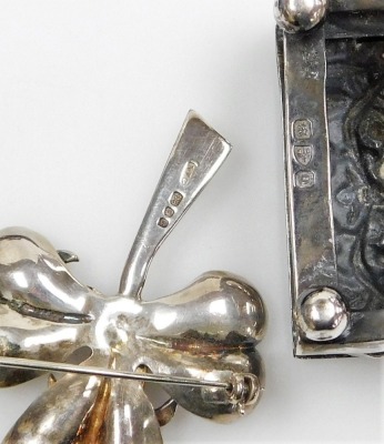 A group of small silver, to include a late Victorian silver match cover, repousse decorated with vacant cartouche, birds, scrolls, etc., Chester 1899, a three leaf clover brooch, 5cm high, boxed, a pair of knife rests, condiment lids, button hook, etc., w - 4