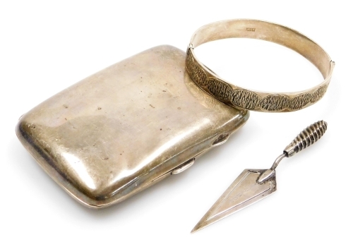 A group of small silver, a cigarette case, of plain form, the interior inscribed with dedication, Birmingham 1925, a bookmark modelled in the form of a trowel, Birmingham 1892, and a hinged bangle, Birmingham 1971, 2¾oz overall.