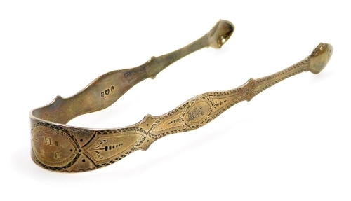 A pair of Georgian silver sugar tongs, with bright cut decoration and initialled, 1oz, 15cm long.